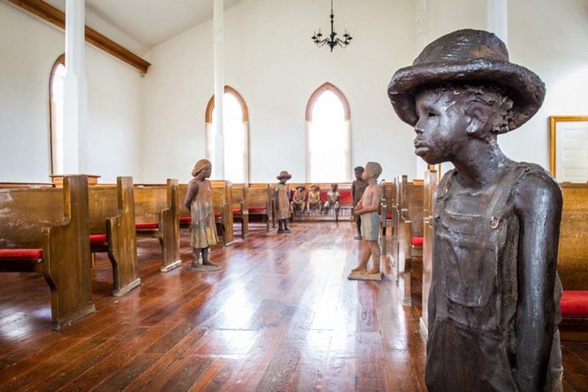 Interior de iglesia con bancas de madera, un pasillo central y una estatua de un niño. 4