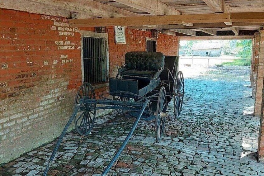 A covered carriage with a brick wall and a cobblestone floor. 2