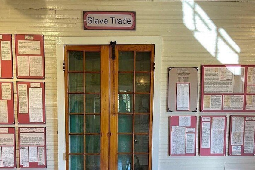 En byggnadsingång med en skylt som lyder ”Slavhandel” och flera informationspaneler på väggarna. 2