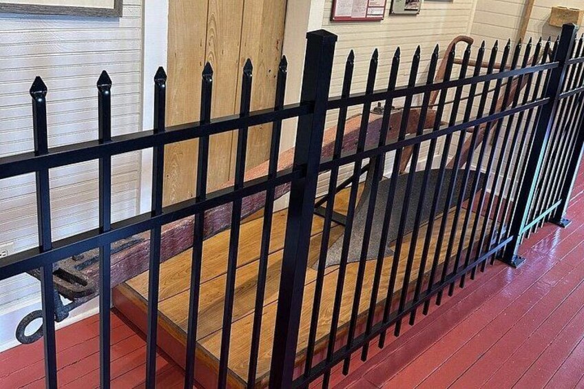 A black metal fence with pointed tops, wooden steps, and a red floor. 3