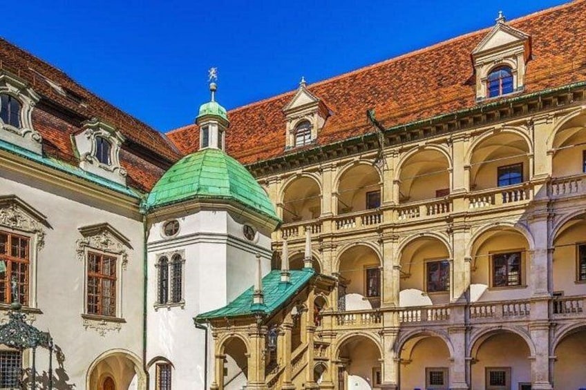 Un edificio storico caratterizzato da una cupola verde, balconi ad arco e tetti in tegole rosse. 4