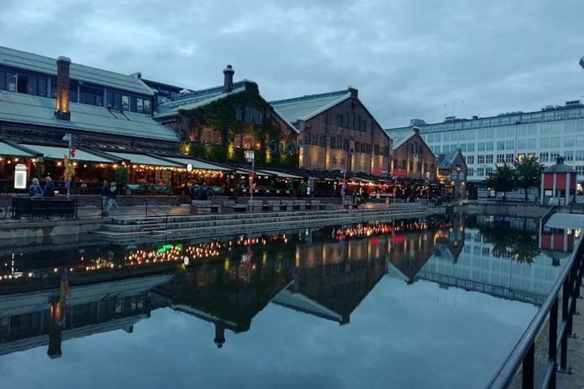 Een waterkant met gebouwen die in het water weerspiegelen, een brug en een rij restaurants. 2