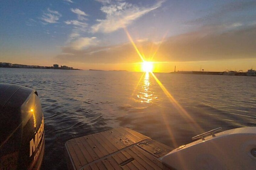 A sunset over a body of water with a boat docked on the left. 4