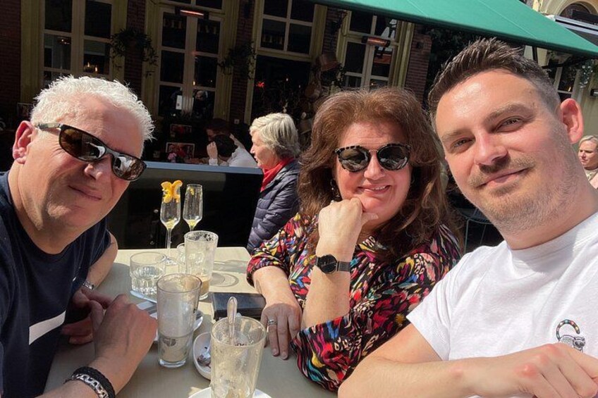 A group of people sitting at an outdoor table with drinks and glasses. 4