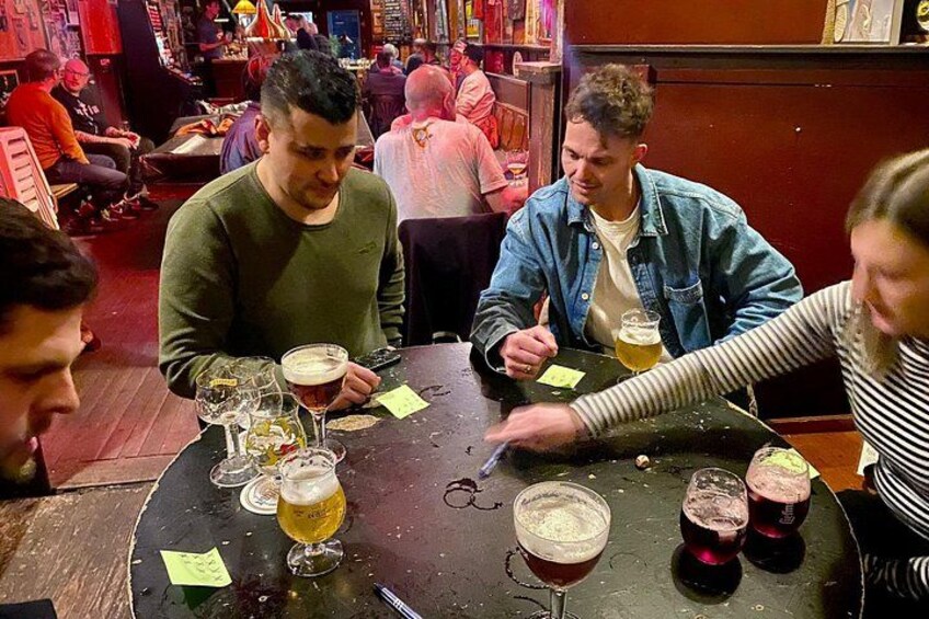 A group of people sitting at a table with various glasses of beer and a few empty bottles. 5