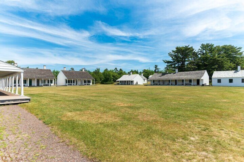 A grassy field with several white houses and a covered walkway. 5