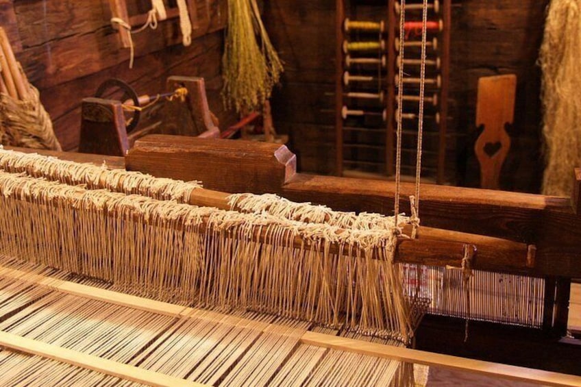 A loom with a wooden frame and a weaving process in progress. 2