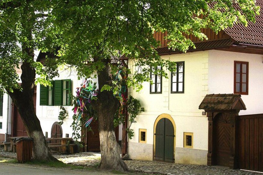 Un bâtiment traditionnel avec une porte verte, une horloge et un arbre devant. 5
