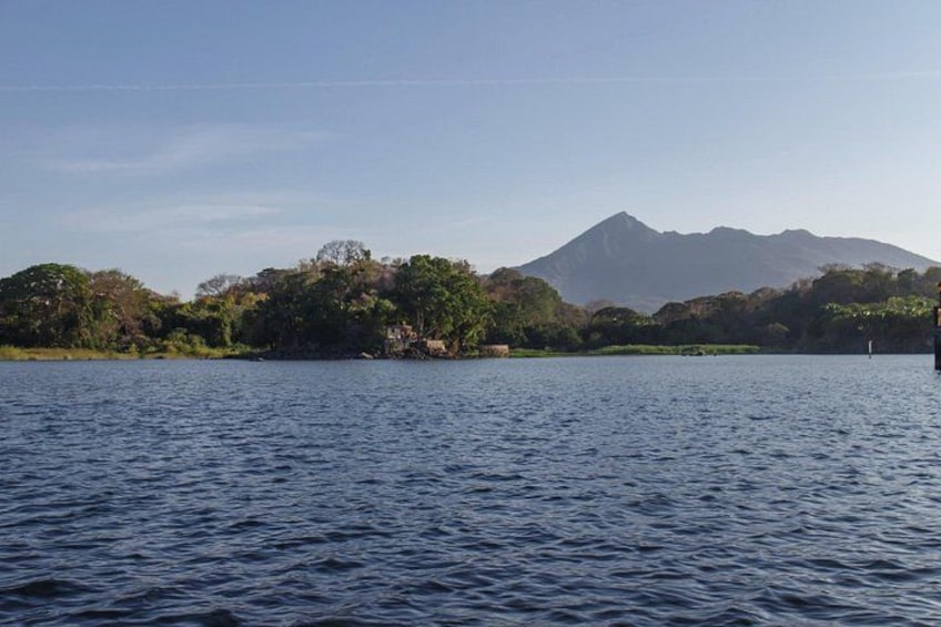 Un lago tranquilo con una isla boscosa y una montaña al fondo. 2