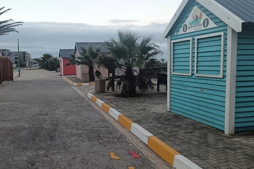 Een gebied aan het strand met een turquoise gebouw met de naam 'Jeffrey's Bay', palmbomen en een zandpad. 3