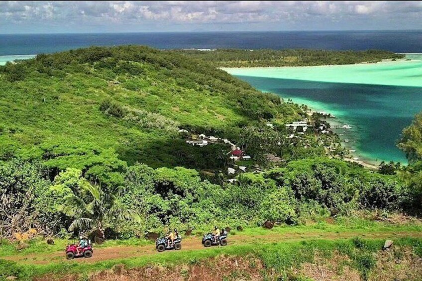 Un paisaje verde exuberante con vista despejada al océano y un pequeño poblado. 2