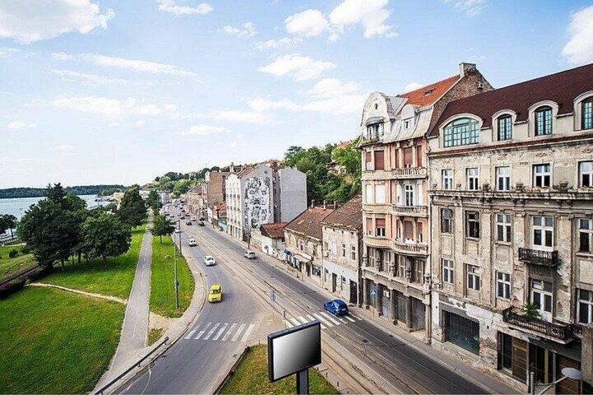 A street with buildings, a road, and a body of water in the background. 1