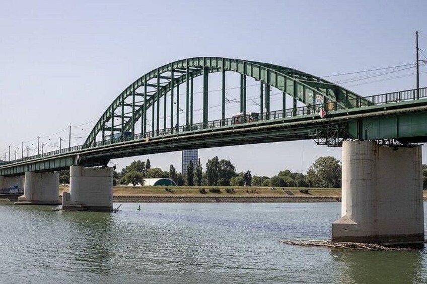 A green metal bridge over a river with concrete supports. 3