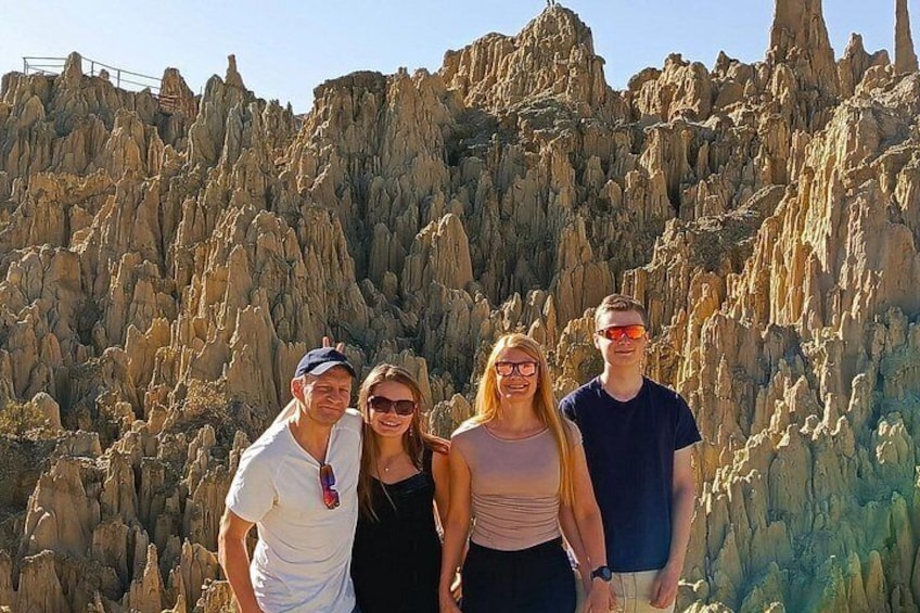 A group of people standing in front of a rocky landscape with prominent geological formations. 1