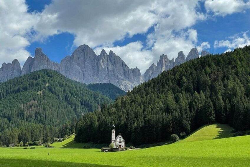 A church on a hill with a mountain range in the background. 1