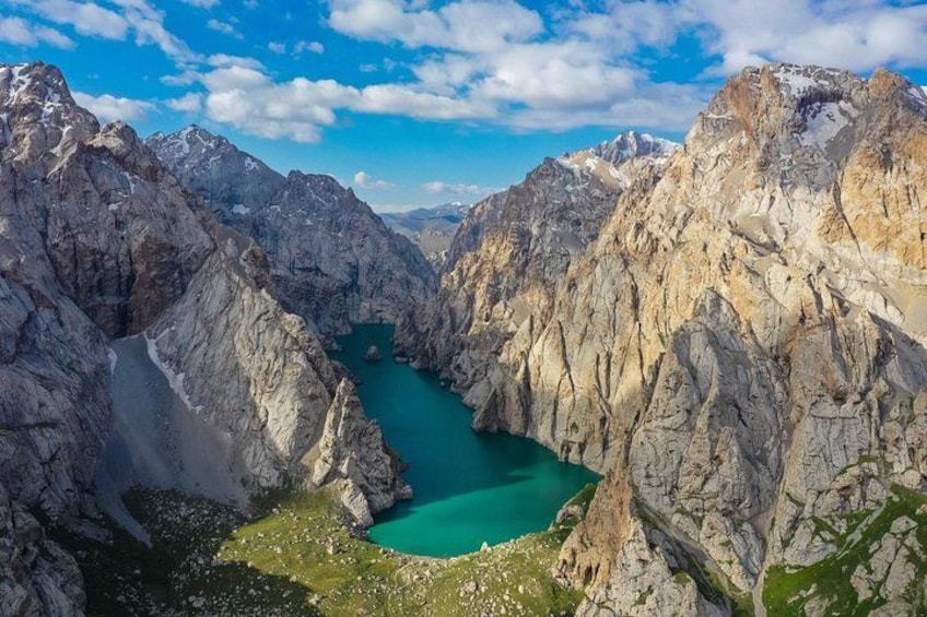 A mountain landscape with a turquoise lake surrounded by rocky cliffs. 1
