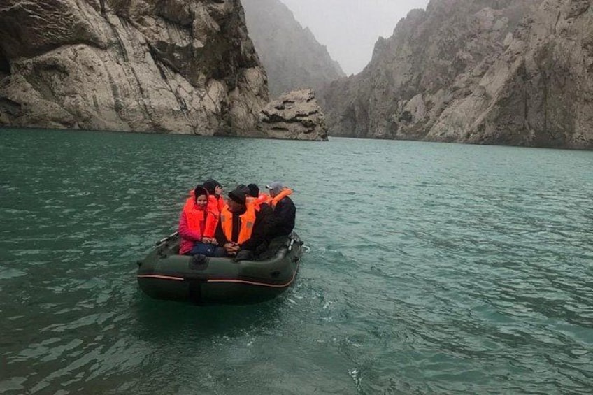 A group of people in a raft on a river surrounded by rocky cliffs. 4