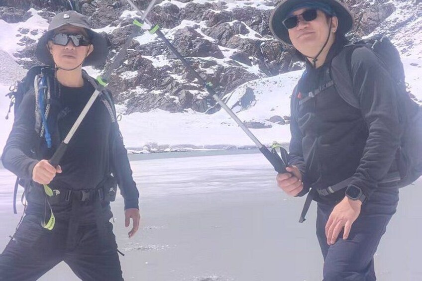 Dos personas de pie en un paisaje nevado, con un cuerpo de agua al fondo. 5