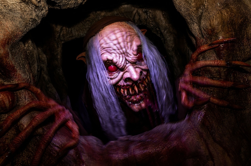 A creature with long hair and red eyes peeking from a cave. 5