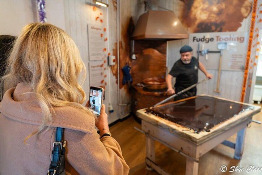 En person fotograferar en process där choklad tempereras med hjälp av en stor industriell maskin. 5