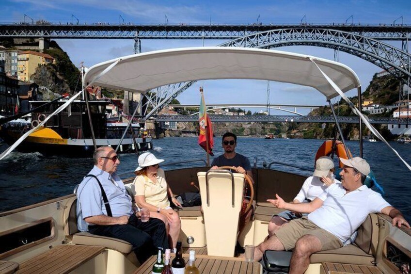 Ein Boot mit Personen an Bord, eine Brücke im Hintergrund und eine Küstenstadt. 1