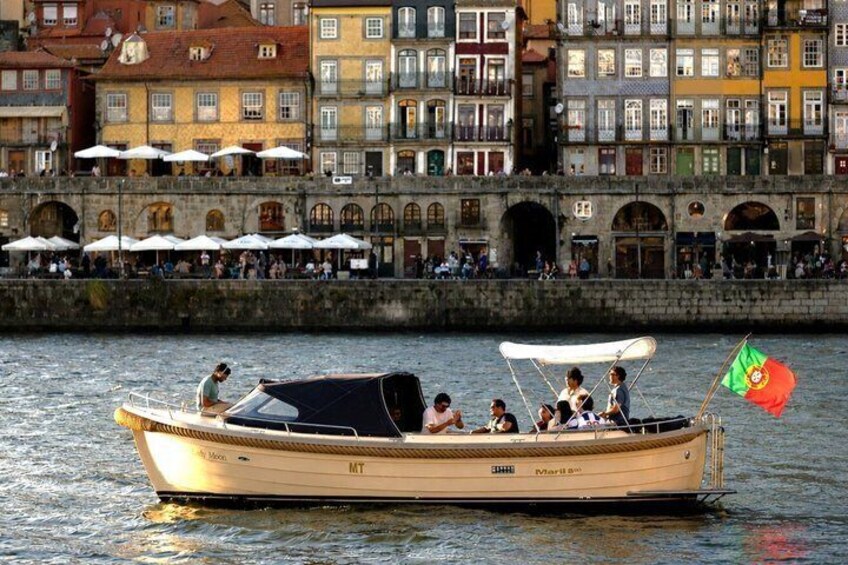 Ein Boot mit Personen, einer Flagge und Gebäuden im Hintergrund. 2