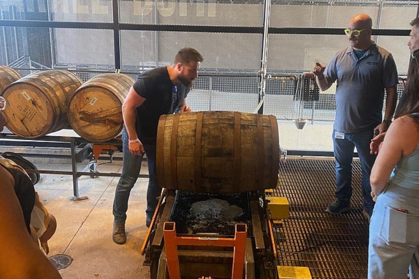 A man operating a barrel chiller, with several wooden barrels in the background. 1
