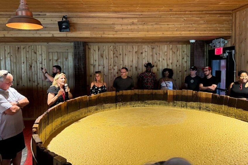 A large circular structure with a yellowish substance inside, surrounded by people observing. 2
