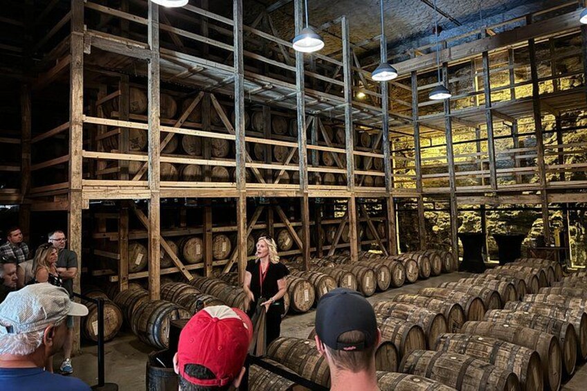 A person presenting in a room with wooden barrels stacked on shelves. 1