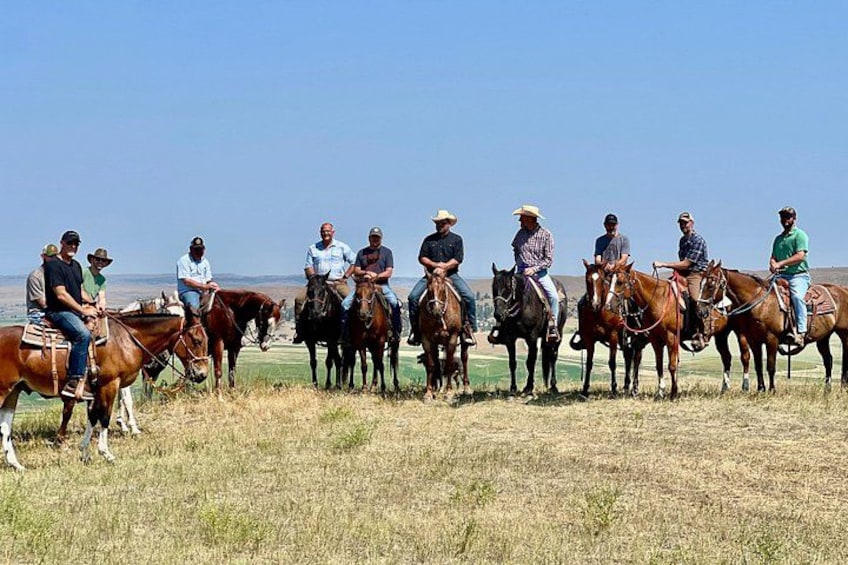 A group of people on horseback in a grassy field with a clear sky. 2
