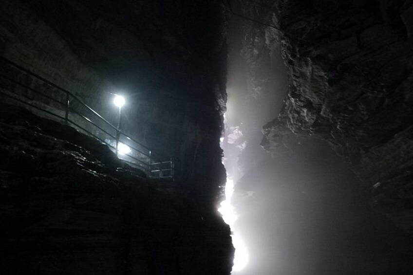 A cave entrance with a metal staircase and a light source. 5