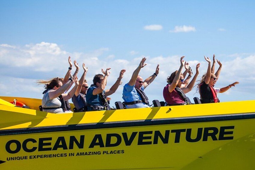 Personas en un bote amarillo con las manos levantadas, con la leyenda 'OCEAN ADVENTURE'. 5