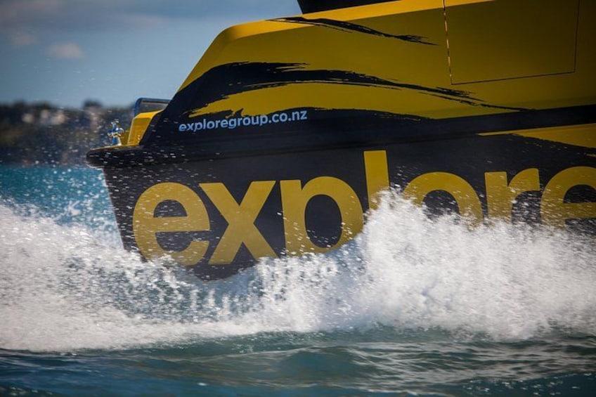 Una lancha rápida con el texto 'exploregroup.co.nz' en el costado, navegando por el agua. 2