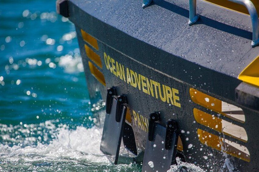 Un bote con la inscripción 'OCEAN ADVENTURE' en su costado, con agua salpicando a su alrededor. 3