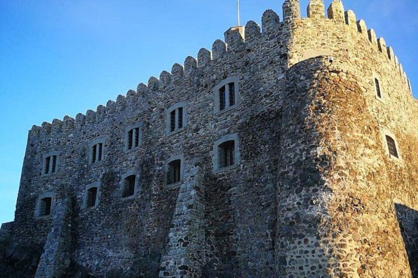 A medieval stone castle with crenellated battlements and multiple windows. 5