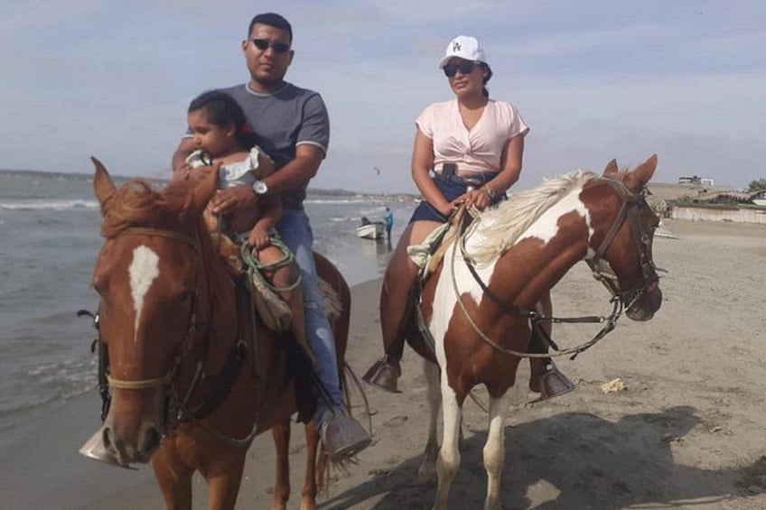 Deux personnes à cheval sur une plage, avec l’océan en arrière-plan. 3