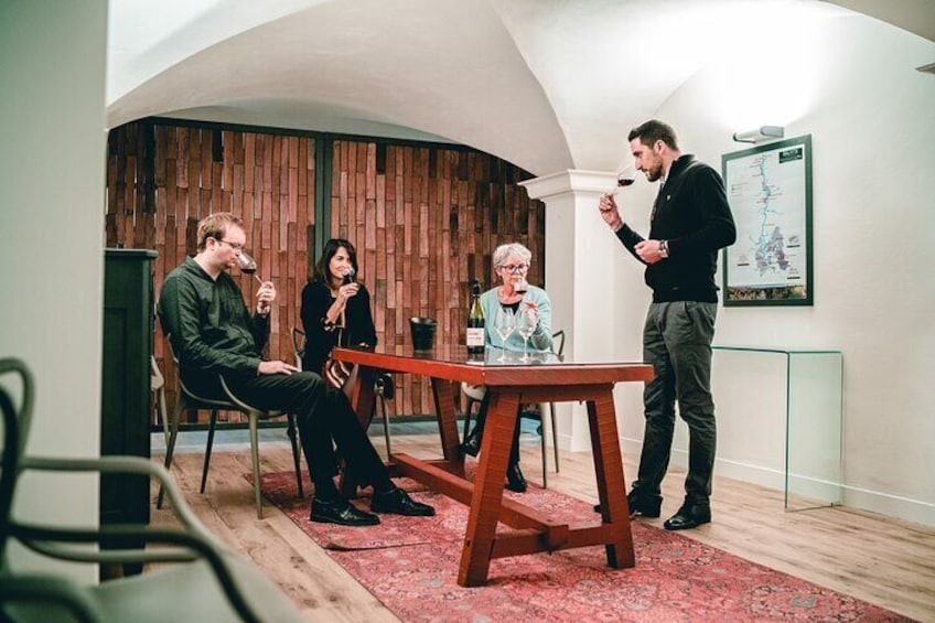 A group of people in a modern room with wooden panel walls, a red carpet, and a table. 1