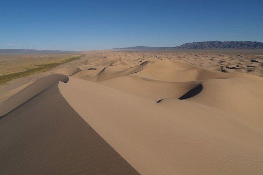 A desert landscape with sand dunes and a clear sky. 4