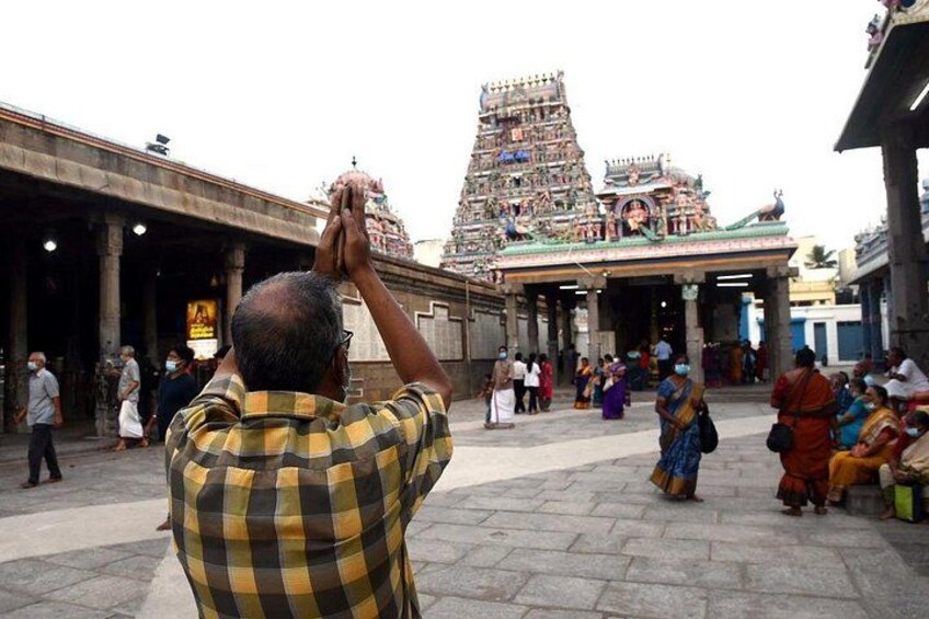 A temple complex with intricate architecture, a person taking a photo, and people in traditional attire. 3