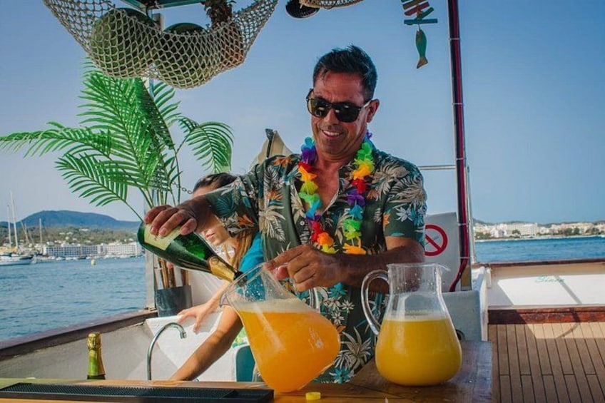 En person hælder drik i et glas på en båd med frit udsyn til havet og en fjerntliggende kystlinje. 5
