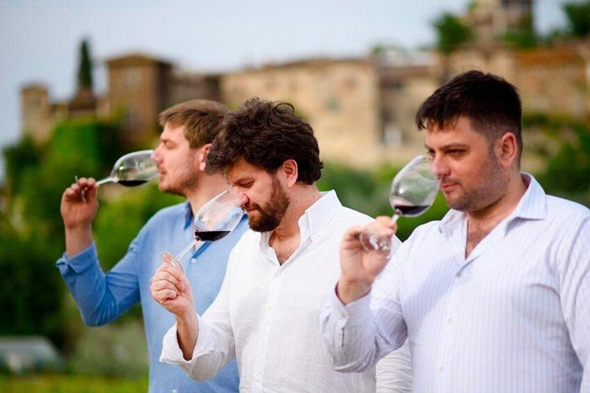 Three men tasting wine outdoors with a historic building in the background. 4