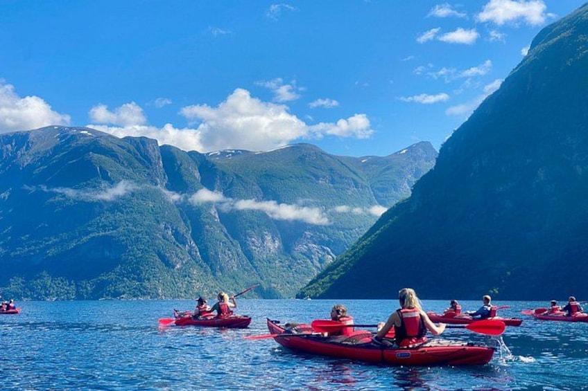 Folk roer i kajakker på en sø omgivet af bjerge. 1