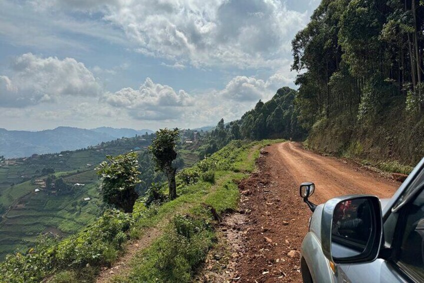 A dirt road winding through a hilly landscape with a car parked on the side. 4