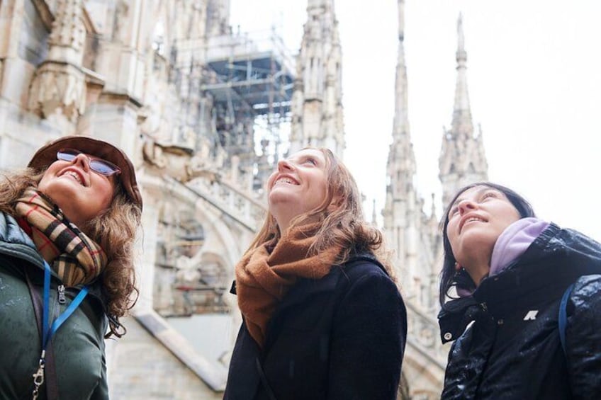 Three people standing in front of a historic building with intricate architecture. 1