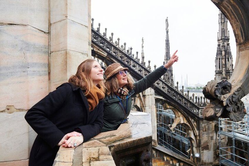 Two people leaning on a stone structure with a gothic architectural bridge in the background. 4