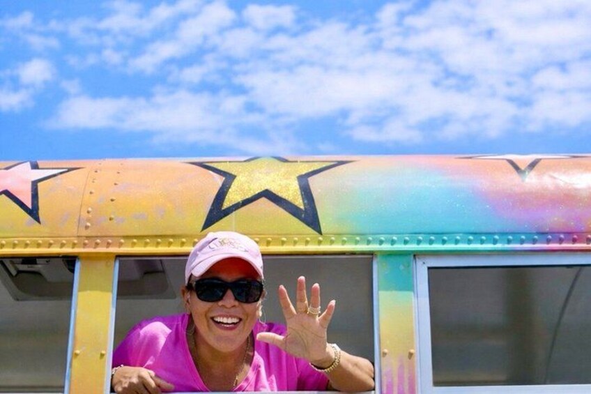 A person waving in front of a colorful bus with stars. 4