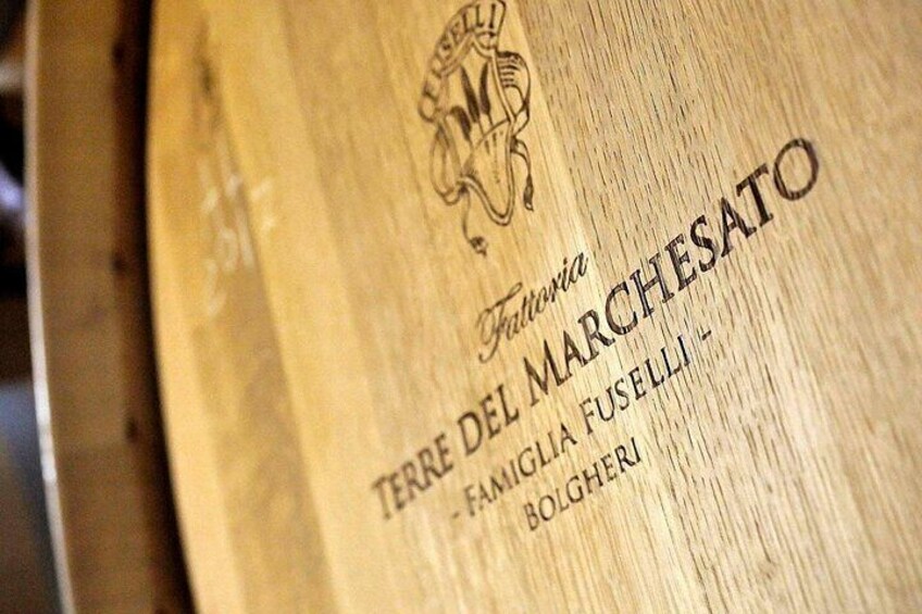 A wooden surface with embossed text reading "Terre del Marchesato" and "Famiglia Fuselli - Bolgheri". 1