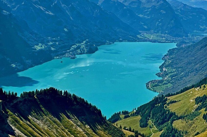 A mountainous landscape with a large turquoise lake surrounded by forested hills. 4