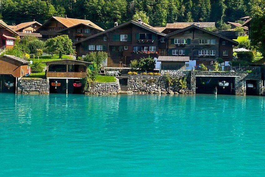 A waterfront village with traditional wooden houses, boats docked at the pier, and lush greenery in the background. 5
