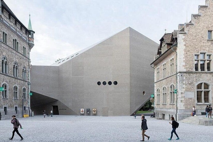 A modern building with a unique geometric design, surrounded by historic architecture. 3